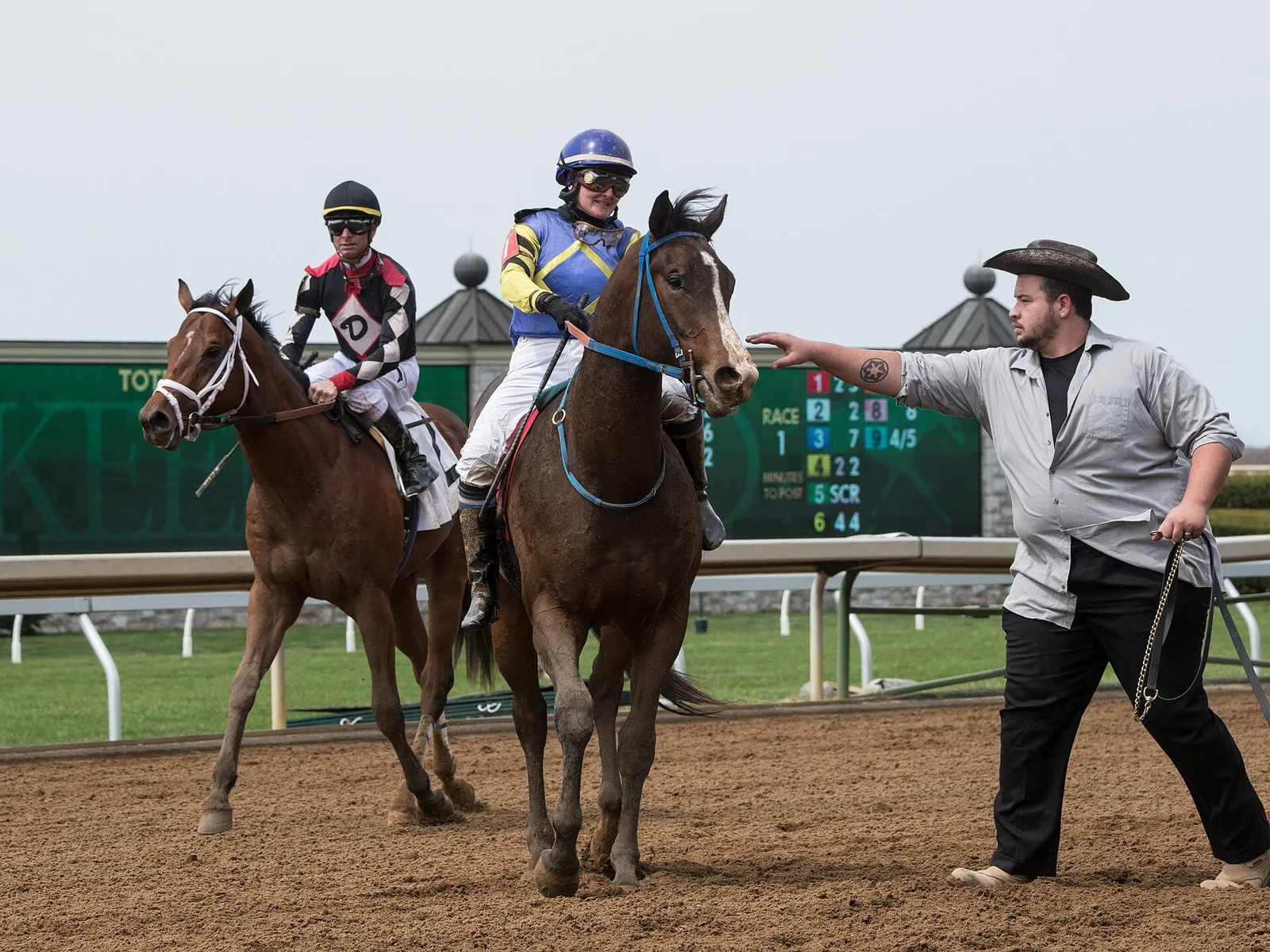 Jockeys bring their horses back past the tote board after a race on the main track at Keeneland in Lexington