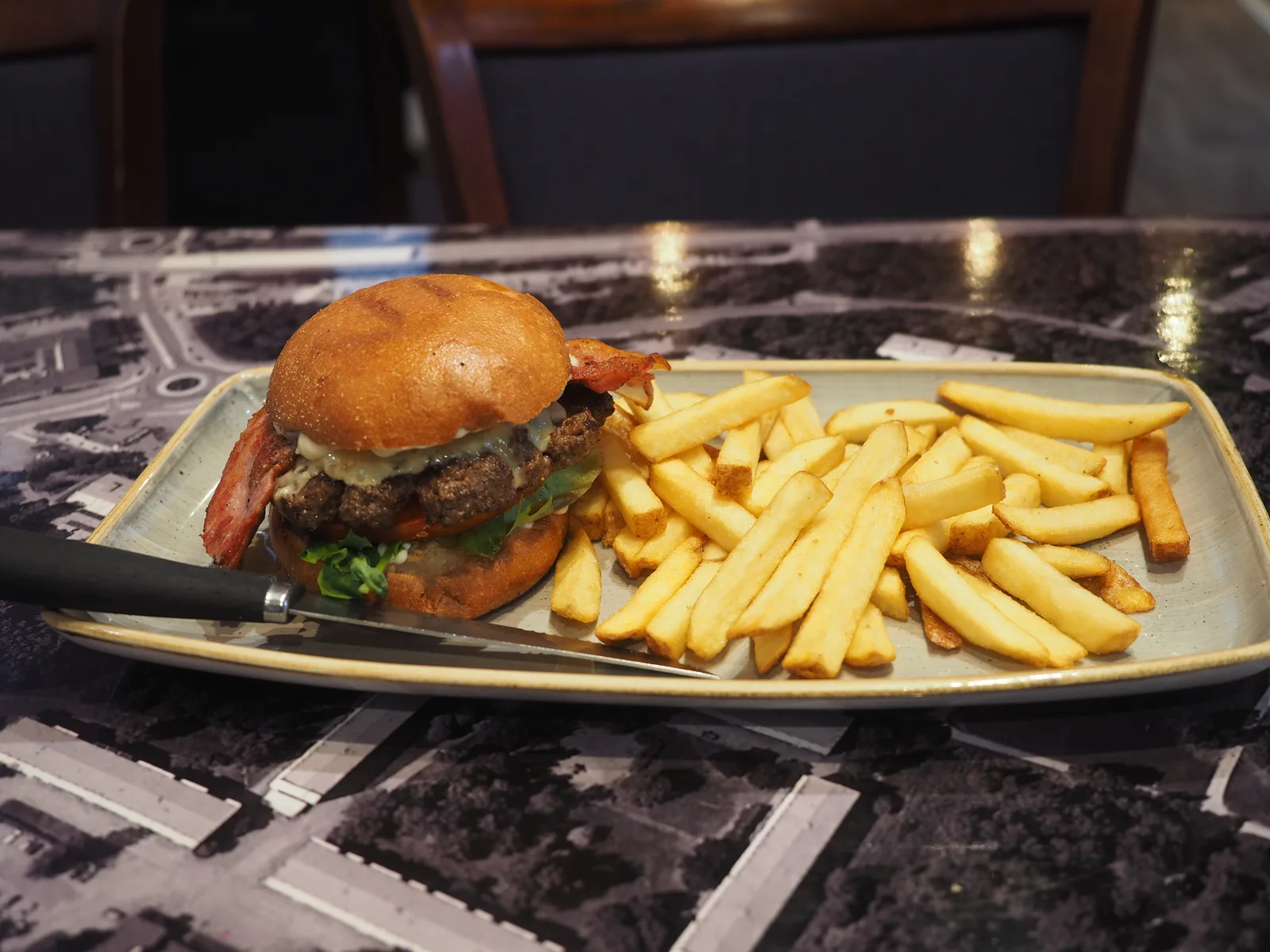 A bacon cheeseburger and fries on a plate at a restaurant called Wanda's, which is not on this list.